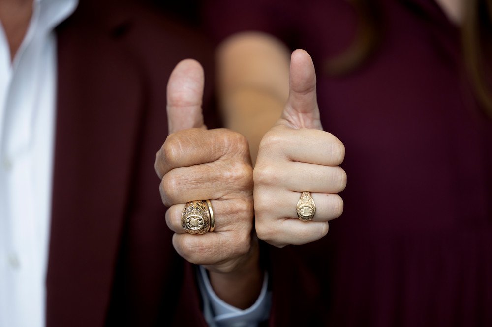 Two Aggies gig 'em with their Aggie rings side by side